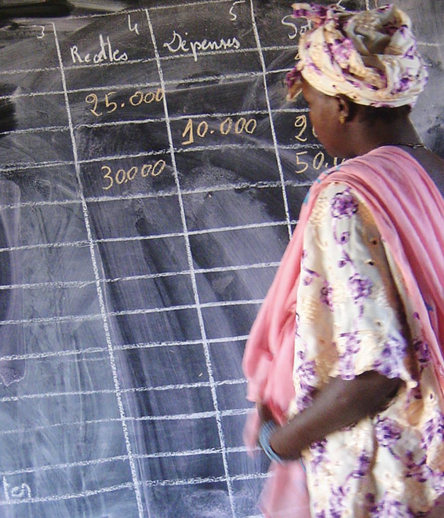 Photo d'une institutrice écrivant au tableau, extraite de la plaquette de promotion des actions de codéveloppement créée pour Coallia par Caramel & Paprika (photo © Coallia)
